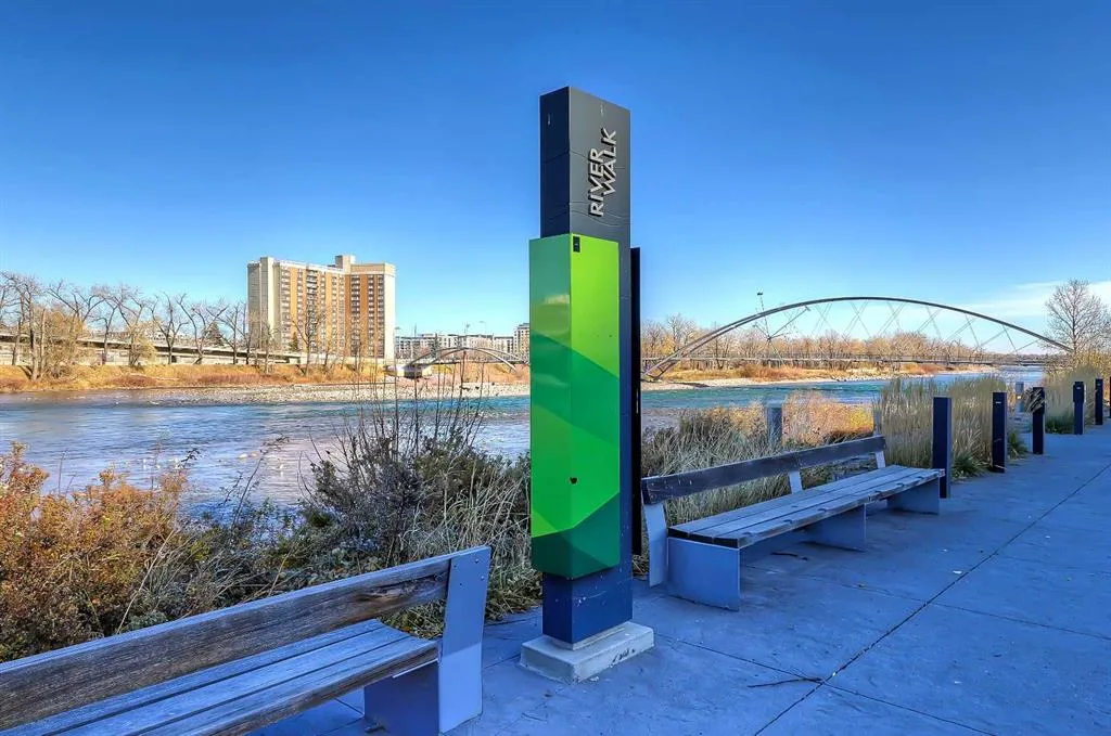RiverWalk pathway signage with a pedestrian bridge over the Bow River