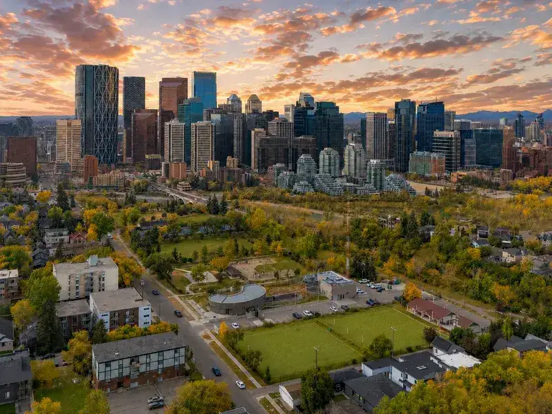 Calgary downtown skyline at golden hour viewed from Renfrew with the Bow River and Rocky Mountains visible